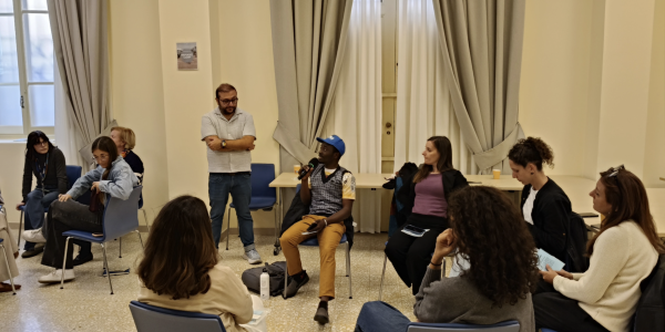 JRS IO staff and partners participating in A Journey Into Exile simulation in Rome. This session was conducted by JRS Canada's Tevfik Karatop. A group of adults sitting around in a circle havinga discussion.